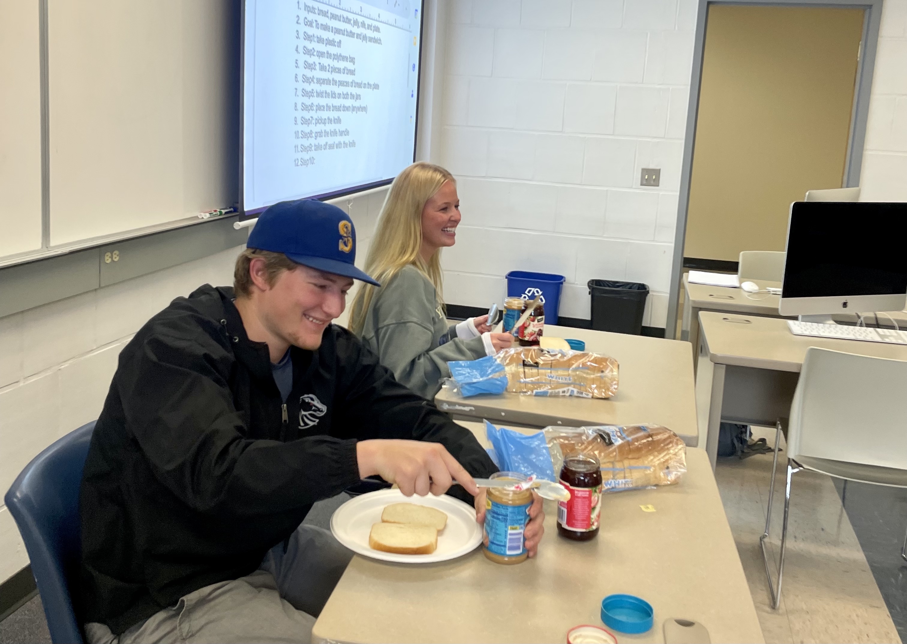 PBJ makers; the image shows two students making peanut butter and jelly sandwiches in a classroom