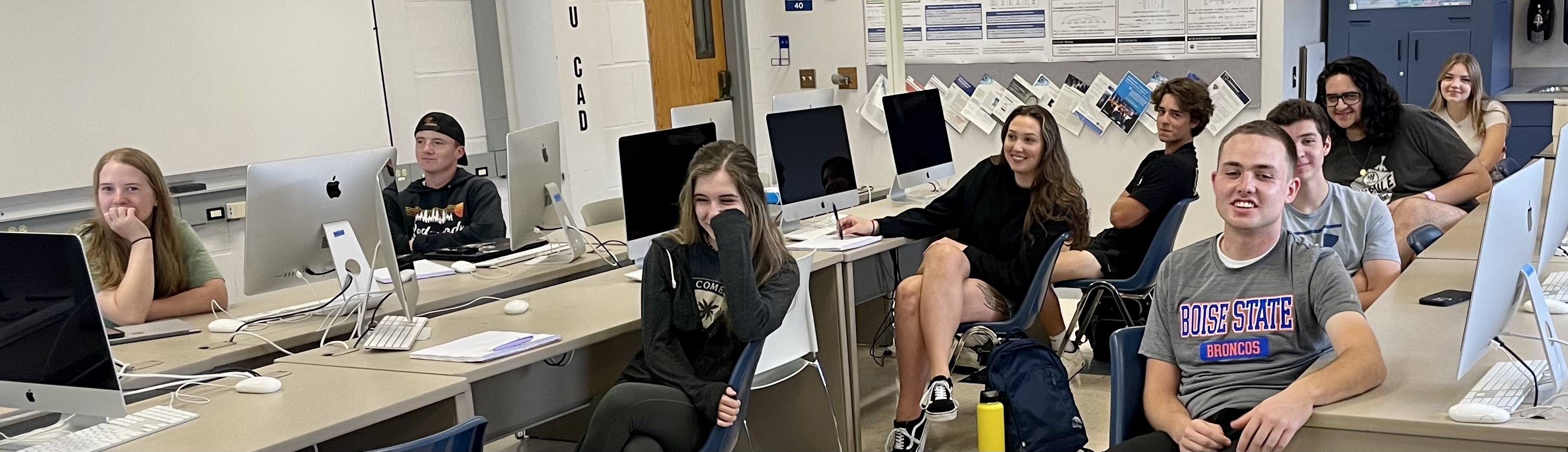 Happy students; the image shows students sitting in a computer lab and smiling